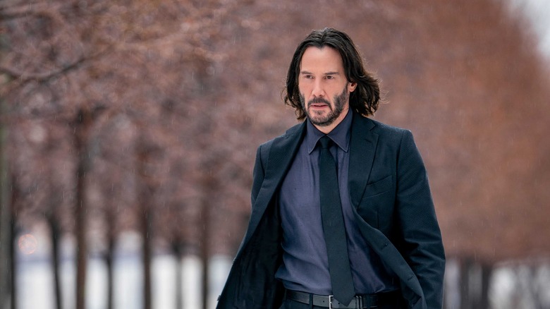 John Wick walking down tree-lined path