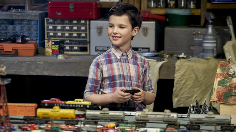 Young Sheldon playing with trains